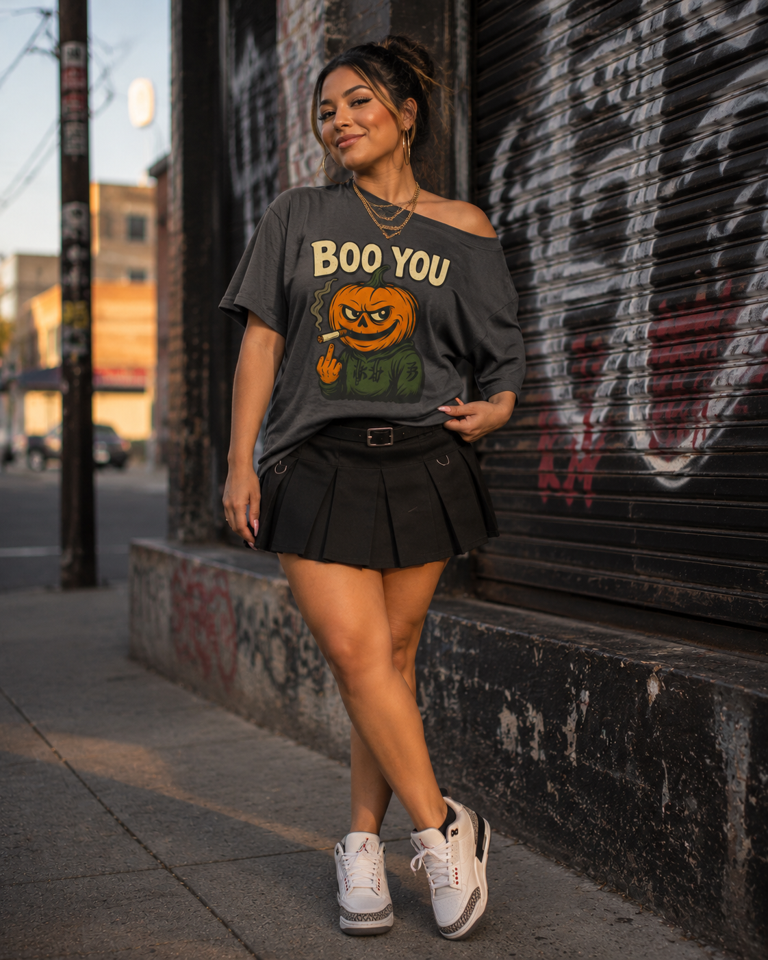 Dark Grey (woman, off-shoulder, pleated skirt, Jordan 3s, graffiti wall) — "Woman in dark grey Boo You Stank Statement Tee styled off-shoulder with a pleated mini skirt and Jordan 3s leaning against a graffiti wall, bold street style"